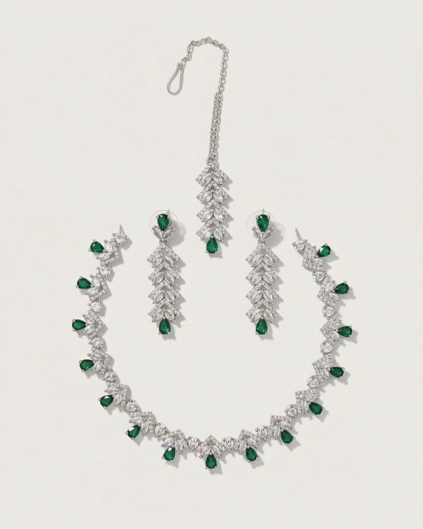 Elegant silver jewelry set with green teardrop gemstones and clear crystals on white background